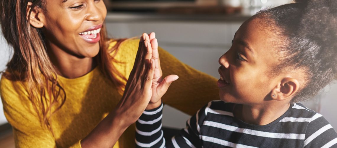Black mother and child high five in kitchen home