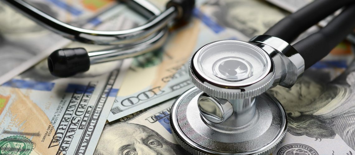 Medical stethoscope on heap of dollar bills. Health care or insurance costs concept. Finance banking audit analytics.