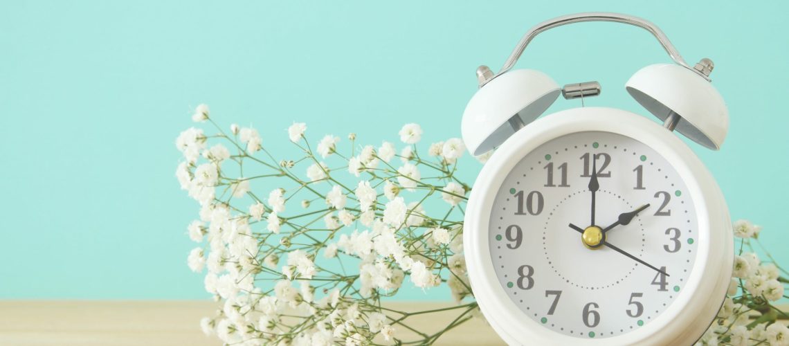 Image of spring Time Change. Summer back concept. Vintage alarm Clock over wooden table