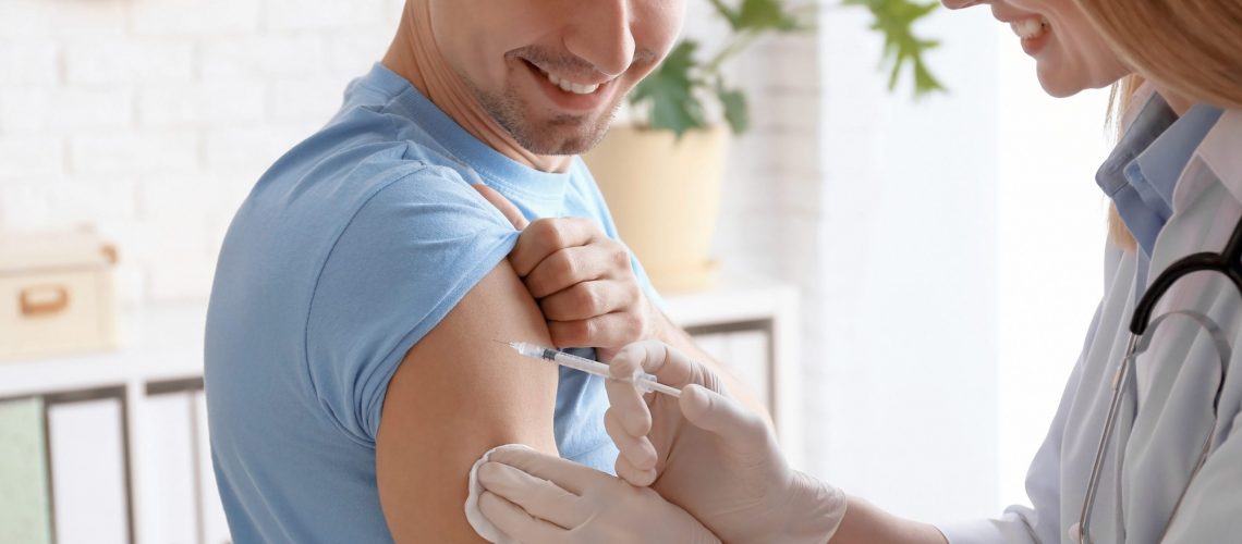 Doctor vaccinating male patient in clinic