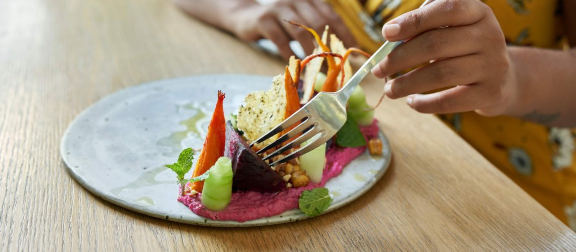 Closeup shot of tasty fine vegetarian plant-based cuisine on artisanal ceramic plate including beets, carrots, vegetable puree, bread, cucumber, mint and extra-virgin olive oil for mindful eating and a nutritious paleo diet.