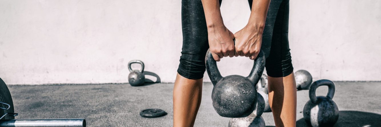 Kettlebell weightlifting woman lifting free weight panoramic banner gym. Hands holding heavy kettle bell for strength training exercise lifestyle.
