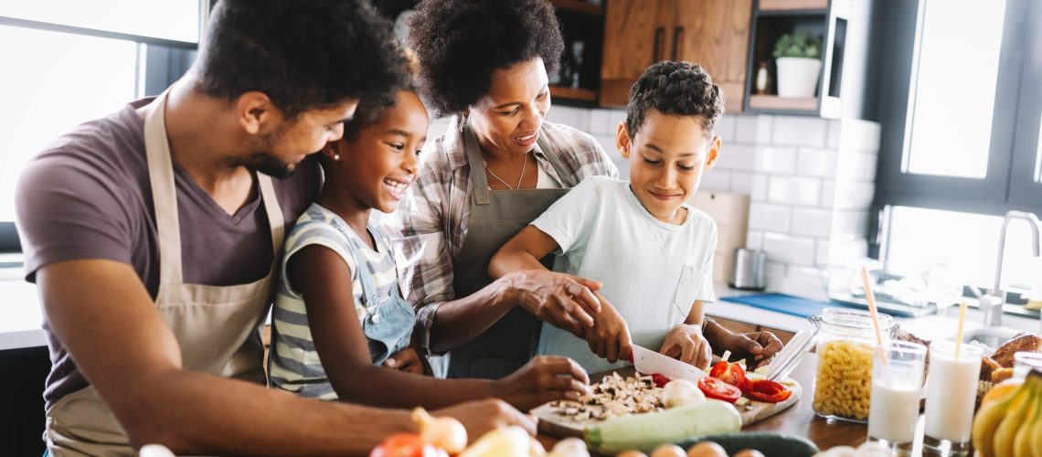 Happy african american family preparing healthy organic food together in kitchen