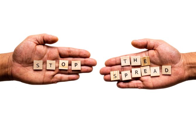 Two hands display the message "STOP THE SPREAD". Public health transmission concept.