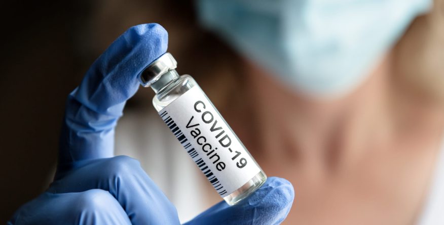 COVID-19 vaccine concept, female doctor holds coronavirus medication in office or laboratory. Bottle with vaccine for corona virus treatment closeup. Clinical trial due to coronavirus pandemic.