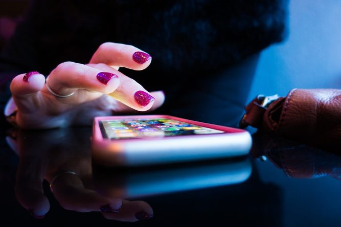 A closeup of a person swiping through a dating app on their phone.