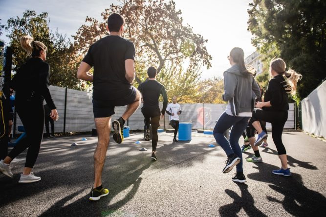 A group of coworkers exercising outside showing employee wellness.