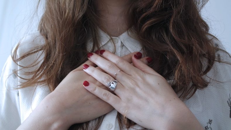 A closeup shot of a woman holding her chest.